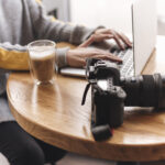 close-up-woman-typing-laptop-coffee-shop